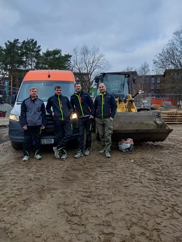 Team von Isac Gartenbau vor Firmentransporter und Radlader auf einer Baustelle in Potsdam