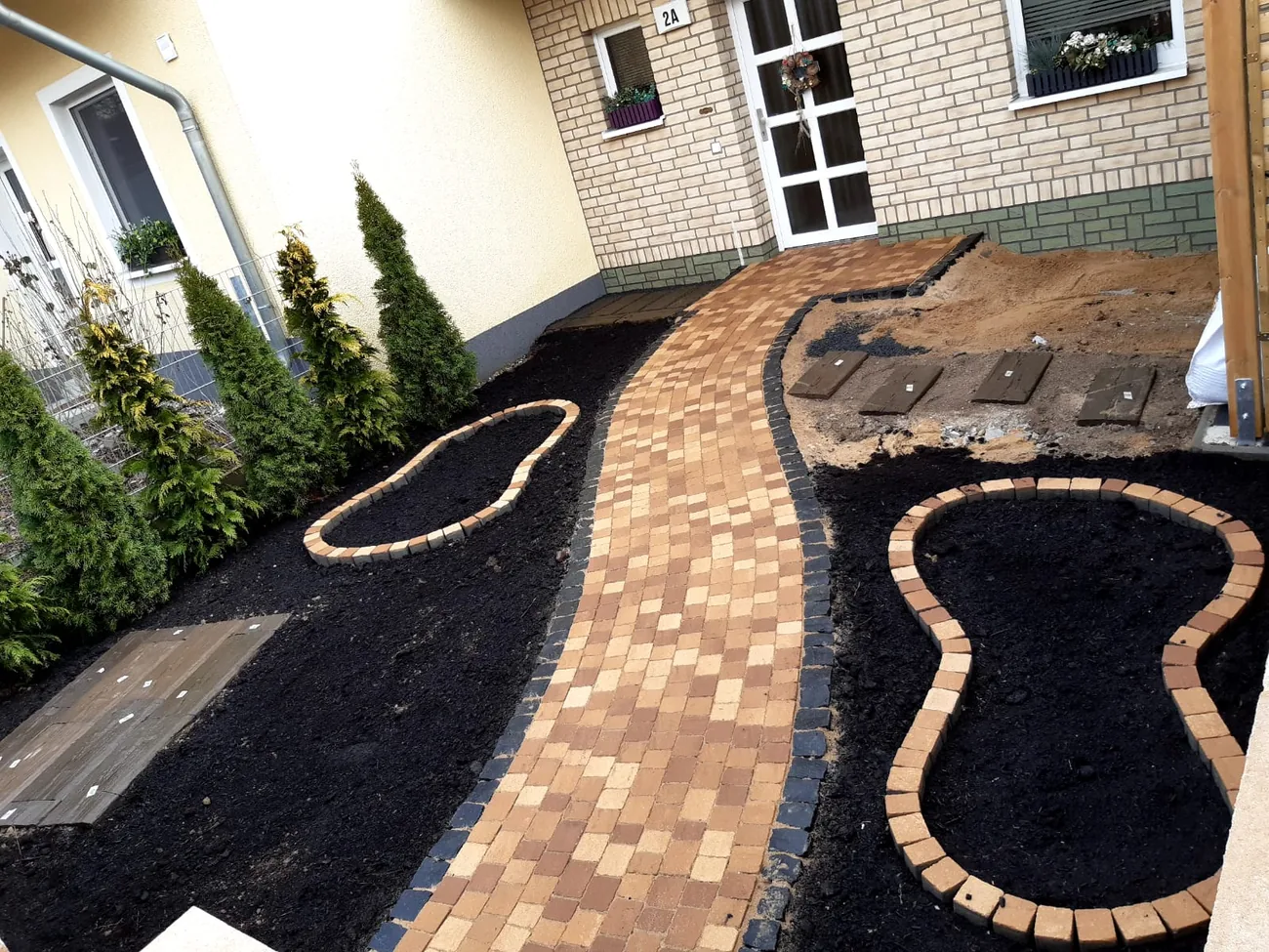 Geschwungener Pflasterweg aus Betonsteinen zum Hauseingang, angelegt von Isac Gartenbau in Potsdam