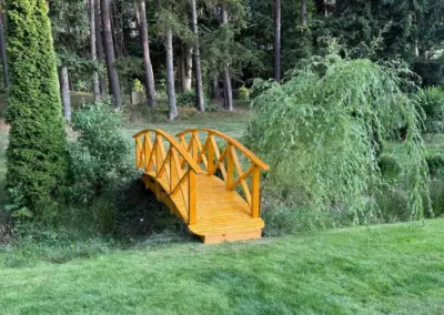 Holzbrücke über einen Graben im parkartigen Garten
