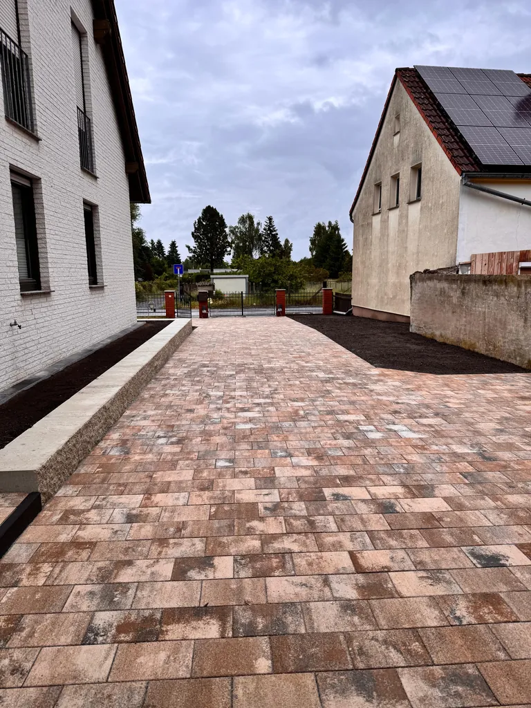 Neue Pflasterfläche mit heller Randeinfassung, Blick vom Hof zur Straße