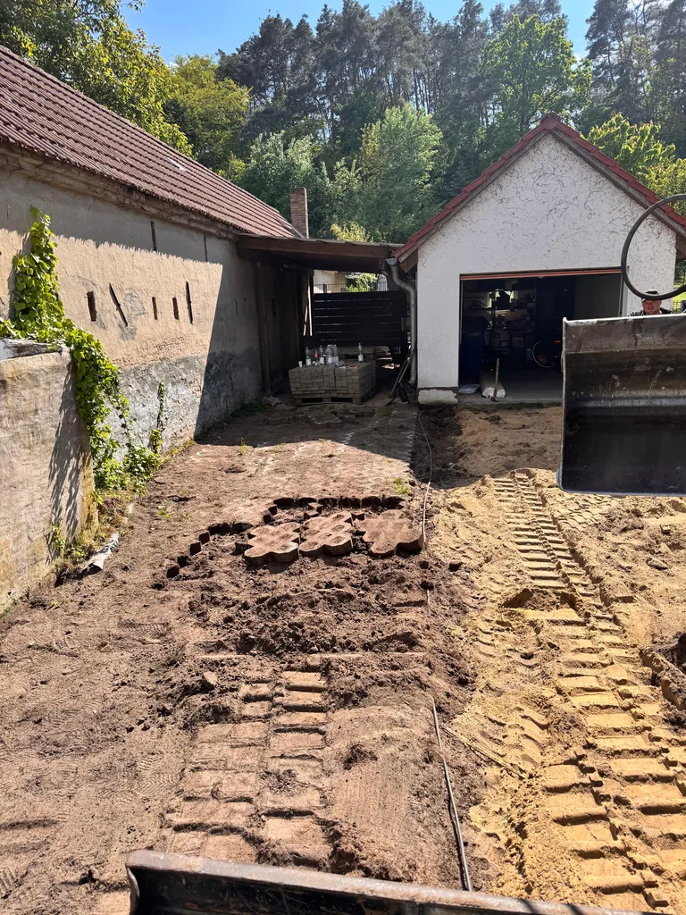 Ausgehobene Zufahrt zwischen Haus und Nebengebäude bis zur Garage im Hof
