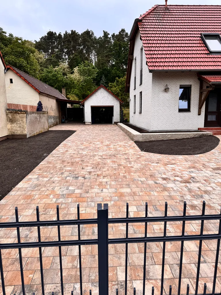 Fertig gepflasterte Einfahrt im Farbmix Rot-Braun-Beige mit Blick zur Garage im Hof