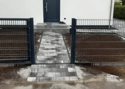 Doppelstabmattenzaun mit Gartentür und gepflastertem Zugang