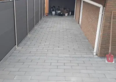 Sichtschutzzaun neben gepflastertem Weg zur Garage