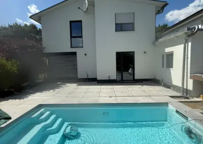 Fertiger Pool mit Ecktreppe vor dem Haus